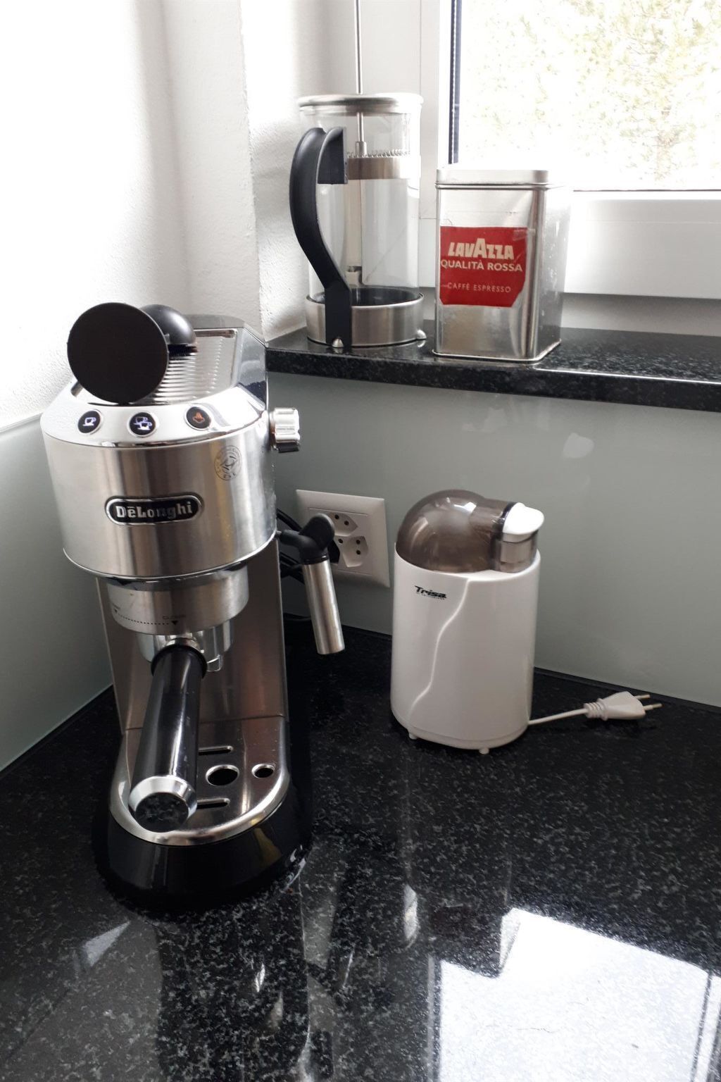 Een koffiezetapparaat, een koffiekan en een voorraad koffie op een aanrecht.