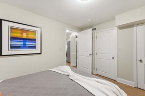 A bedroom with a bed, a framed picture on the wall, and a hallway leading to a closet. - Dupont Circle 1BR with laundry/AC/kitchen (Washington)