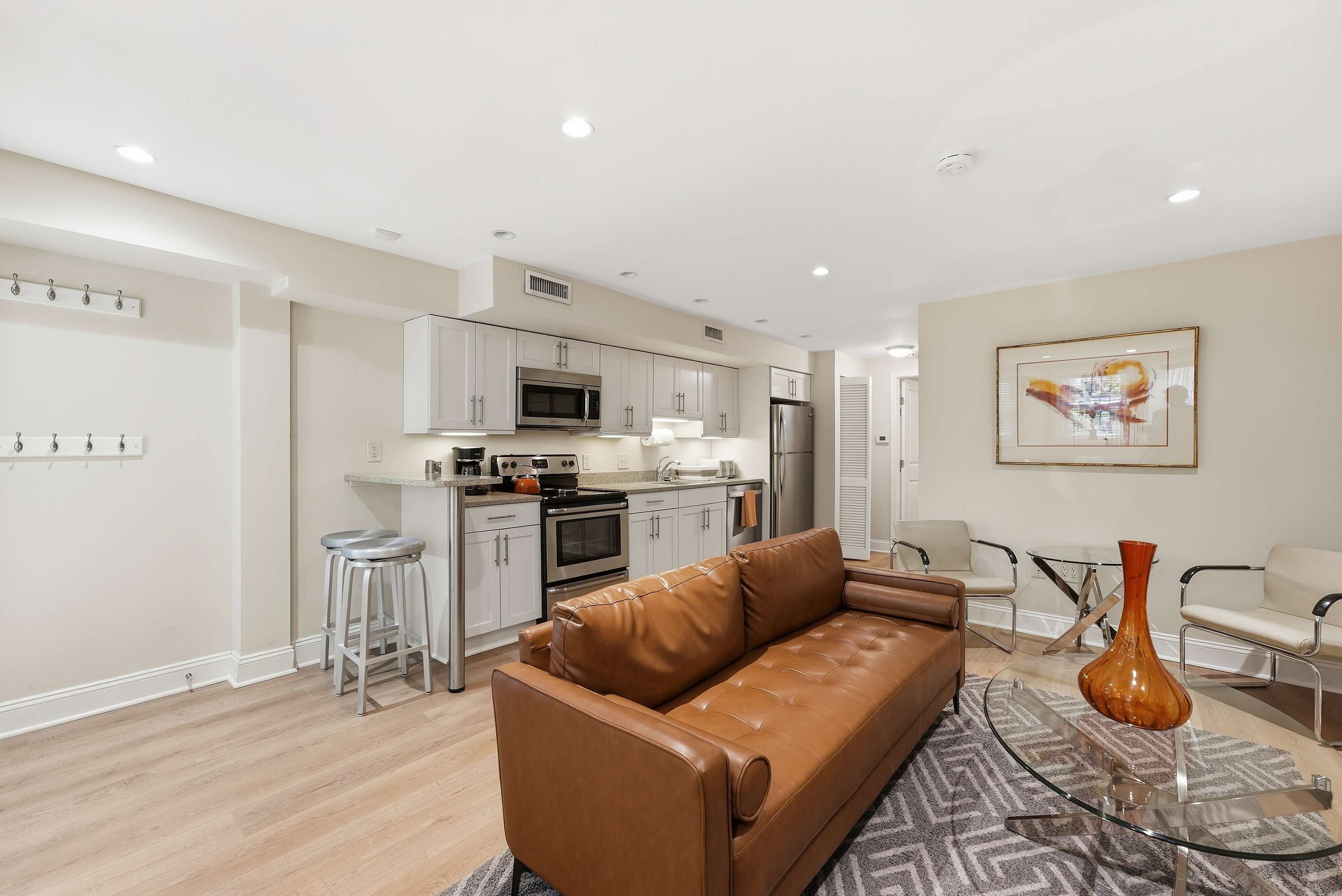 A modern kitchen with stainless steel appliances, a brown leather sofa, and a glass coffee table.