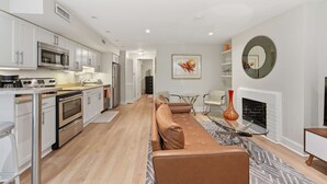 A modern kitchen with stainless steel appliances, a dining area with a leather sofa, and a fireplace. - Dupont Circle 1BR with laundry/AC/kitchen (Washington)