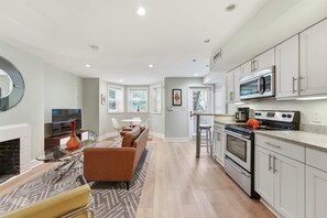 A modern kitchen with stainless steel appliances, a dining area with a glass table and leather chairs, and a living room with a fireplace. - Dupont Circle 1BR with laundry/AC/kitchen (Washington)
