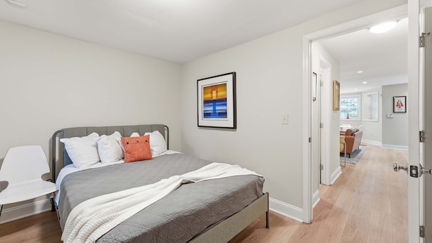 A bedroom with a bed, a bedside table, a chair, and a door leading to another room. - Dupont Circle 1BR with laundry/AC/kitchen (Washington)