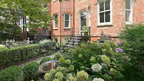 A brick building with a small garden, a visible number '1603' on the door, and a metal staircase leading to the entrance. - Dupont Circle 1BR with laundry/AC/kitchen (Washington)