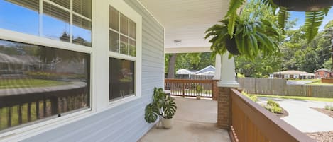 En inglasad veranda med ett betonggolv, krukväxter och utsikt över en bostadsgata.