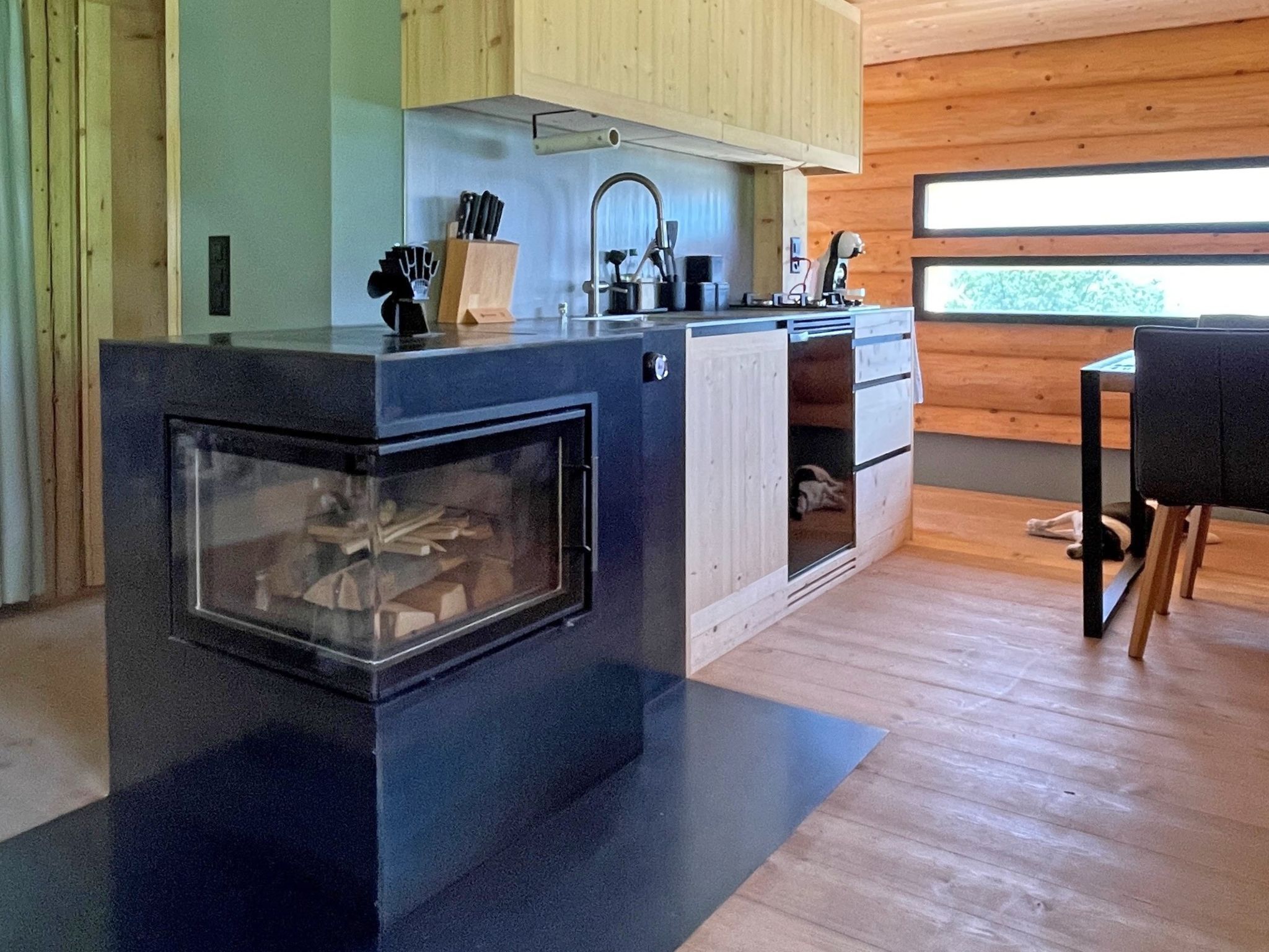 Eine moderne Küche mit eingebautem Herd, Holzschränken und einem Fenster, das für natürliches Licht sorgt.