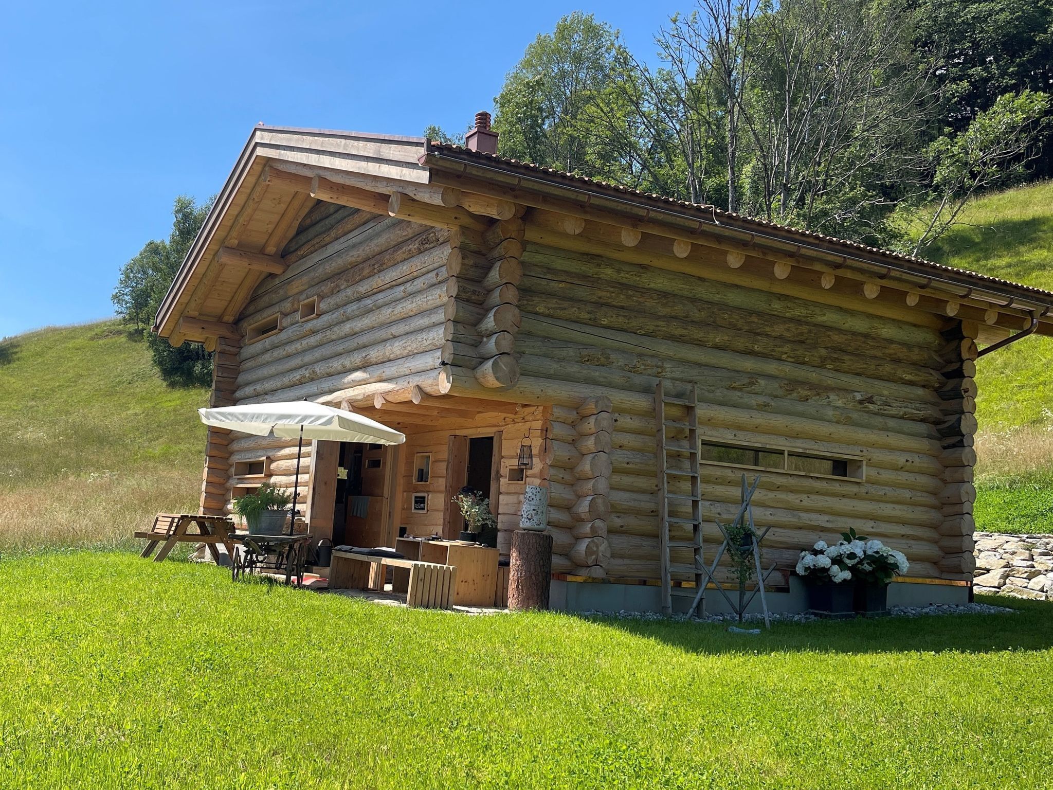 Eine Blockhütte mit einer Terrasse, einem Tisch und einem Stuhl.