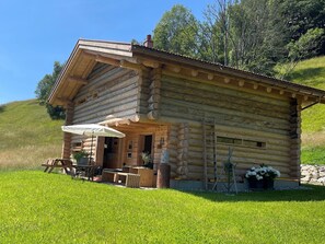 Eine Blockhütte mit einer Terrasse, einem Tisch und einem Stuhl.
