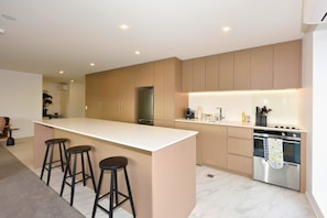 Eine moderne Küche mit einer zentralen Kochinsel, Barhocker, einem eingebauten Backofen und einem Edelstahl-Kühlschrank.