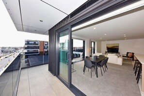 A modern apartment with a balcony, a dining area, and a living space with a TV. - Luxury Central City Sub Penthouse (Christchurch)