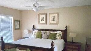 A bedroom with a large bed, a nightstand, a chair, a ceiling fan, and two framed pictures on the wall. - Casa Bearclaw Family Getaway Disney4 Miles 2 bedroom/2bathroom Pet Friendly (Kissimmee)