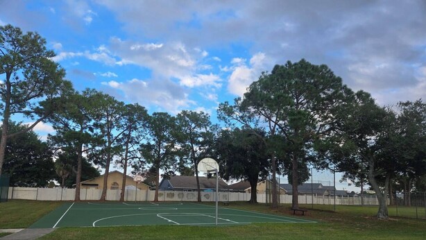 An outdoor basketball court with a green surface, surrounded by trees and a white fence. - Casa Bearclaw Family Getaway Disney4 Miles 2 bedroom/2bathroom Pet Friendly (Kissimmee)