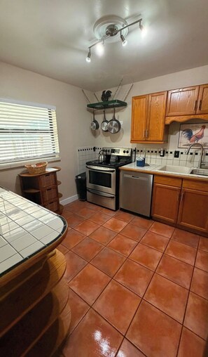 A kitchen with a stove, oven, and dishwasher. There are wooden cabinets and a window with blinds. - Casa Bearclaw Family Getaway Disney4 Miles 2 bedroom/2bathroom Pet Friendly (Kissimmee)