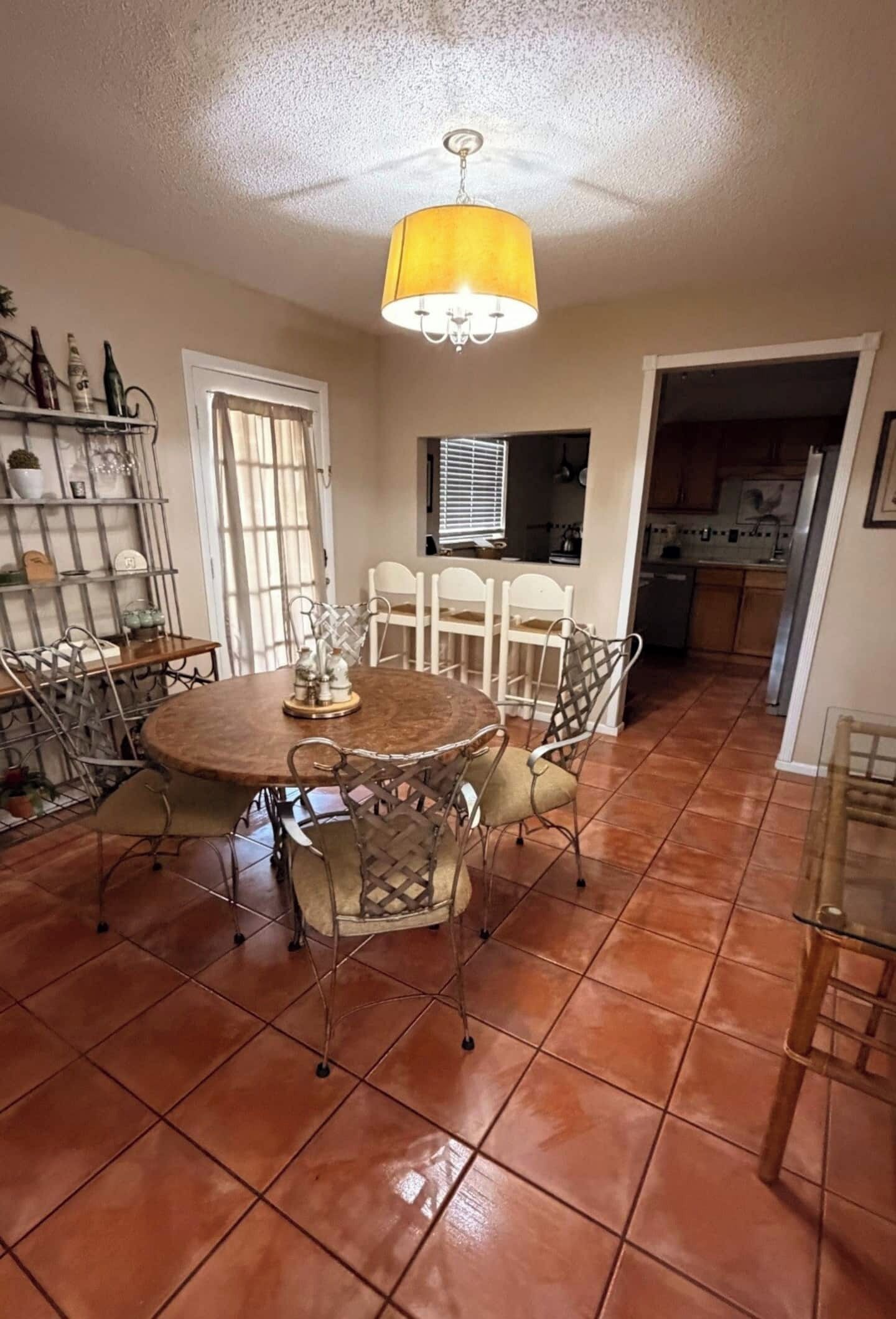 A dining area with a round table, chairs, and a chandelier.