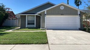 A residential house with a garage, a covered porch, and a well-maintained lawn. - Casa Bearclaw Family Getaway Disney4 Miles 2 bedroom/2bathroom Pet Friendly (Kissimmee)