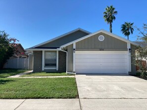 A residential house with a garage, a covered porch, and a well-maintained lawn. - Casa Bearclaw Family Getaway Disney4 Miles 2 bedroom/2bathroom Pet Friendly (Kissimmee)