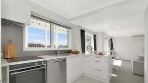 Eine moderne Küche mit Einbauofen, Geschirrspüler und großem Fenster mit Blick ins Freie.