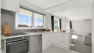 A modern kitchen with a built-in oven, a dishwasher, and a large window providing a view of the outdoors.