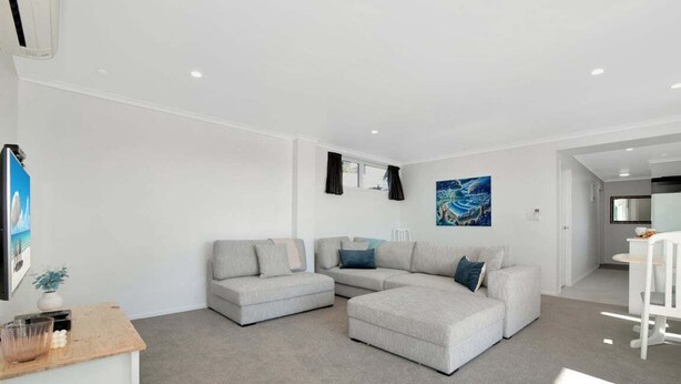 Ein modernes Wohnzimmer mit einem Ecksofa, einem kleinen Tisch und einem Bild an der Wand.
