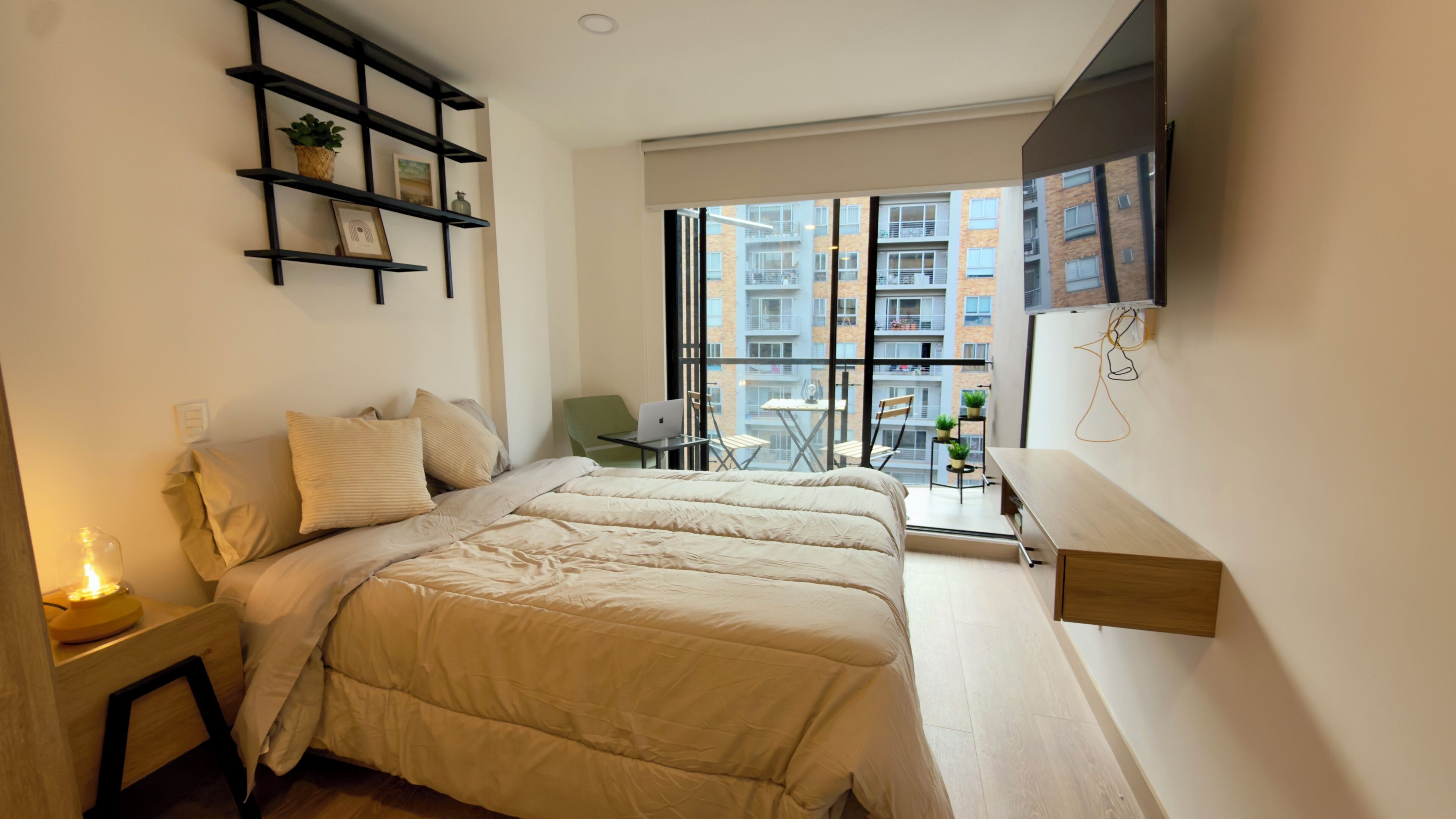 A modern bedroom with a bed, bedside table, and a small desk with a chair.