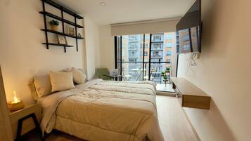 A modern bedroom with a bed, bedside table, and a small desk with a chair.