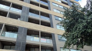 En flervåningsbyggnad med en modern design, utrustad med balkonger, stora fönster och en grind vid entrén.