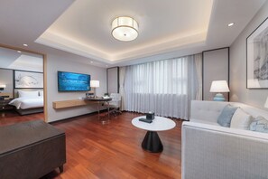 Una habitación de hotel moderna con una cama, un sofá, una mesa de comedor y un televisor fijado a la pared.