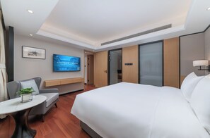 A hotel room with a bed, a desk, a chair, a TV, and a door.