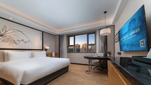 A hotel room with a large bed, a desk, a chair, a TV, and a city view. - Beijing Yiho Hotel (Beijing)