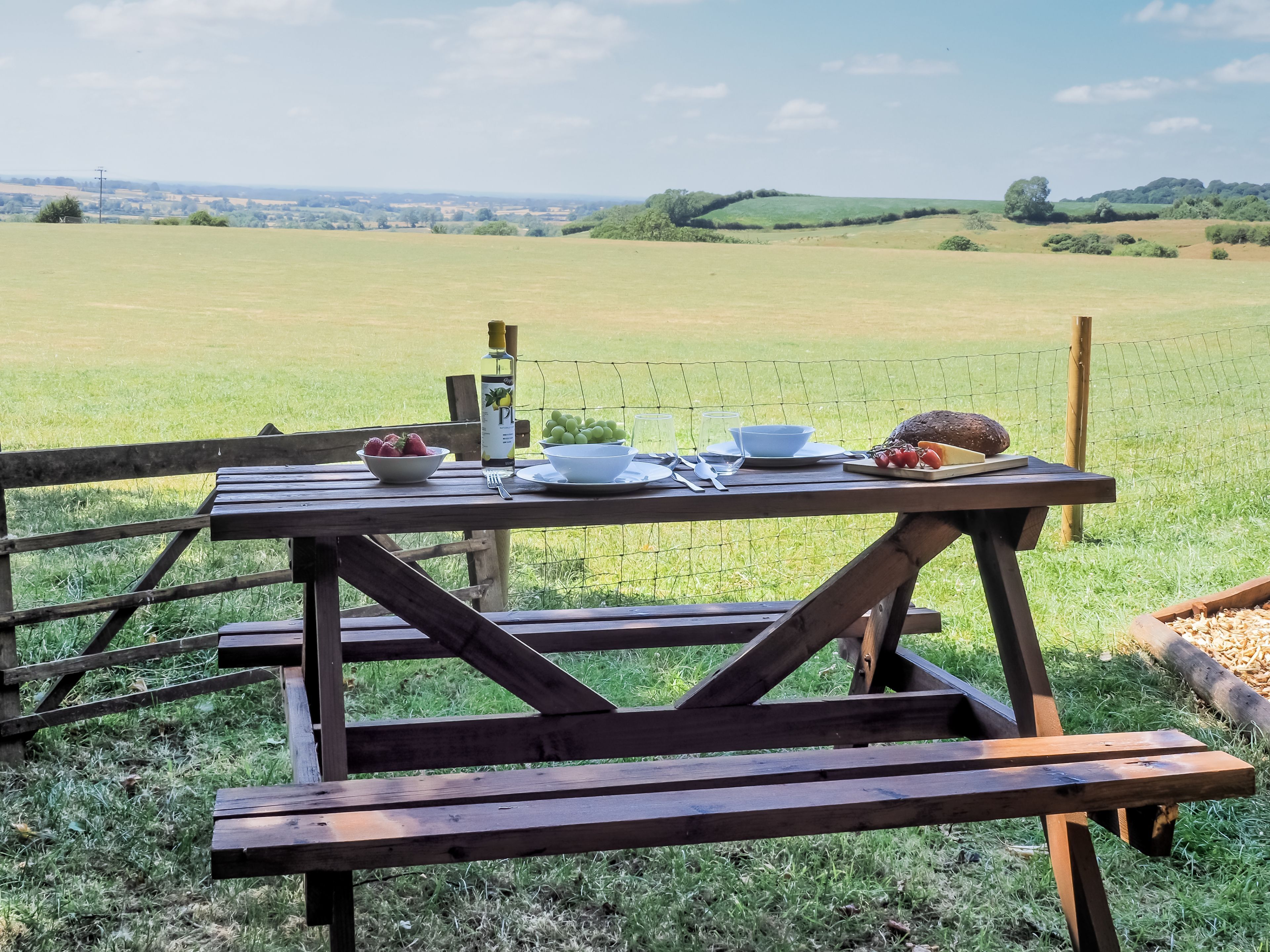 A picnic table set up in a grassy field with a view of the countryside.