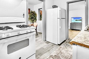 Eine moderne Küche mit Gasherd, weißem Kühlschrank und Meerblick durch ein Fenster.