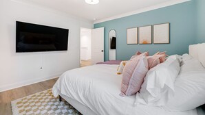 A bedroom with a bed, a flat-screen TV mounted on the wall, a mirror, and three framed artworks. - Hot tub, Mini golf, Fire pit, Game room, Sleeps 14 (Charlotte)
