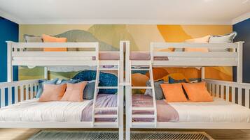 Habitación con literas, una escalera, almohadas y un mural de pared colorido.