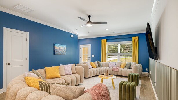 A living room with a sectional sofa, a small round table, and a television mounted on the wall. - Hot tub, Mini golf, Fire pit, Game room, Sleeps 14 (Charlotte)