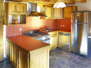 A kitchen with wooden cabinets, a gas stove, a built-in oven, a dishwasher, and a stainless steel refrigerator.