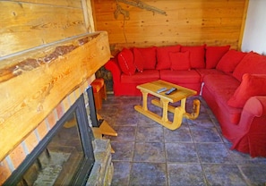 A cozy room with a wooden interior, a red sofa, and a small wooden table with a remote control.