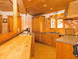 Una cocina de madera con una isla grande, un salpicadero de ladrillo y un fregadero de acero inoxidable.