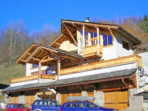 A multi-story wooden chalet with a balcony, stone foundation, and a car parked in front. - Balcon du Paradis by Interhome (Peisey-Nancroix)