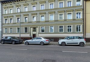 A multi-story building with a row of parked cars in front.