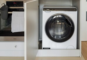 A compact washer and dryer unit with a control panel and a hanging rack. - Wola Ratusz Comfort Apartment (Warszawa)