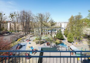 A playground with various play equipment, surrounded by trees and buildings. - Wola Ratusz Comfort Apartment (Warszawa)