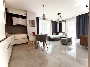 A modern hotel room with a dining area, a bed with a headboard, a small table, and a seating area. - Bulwary Książęce Central Apartment (Wrocław)