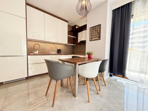 Eine moderne Küche mit weißen Schränken, einem Holztisch und Stühlen mit Holzbeinen.