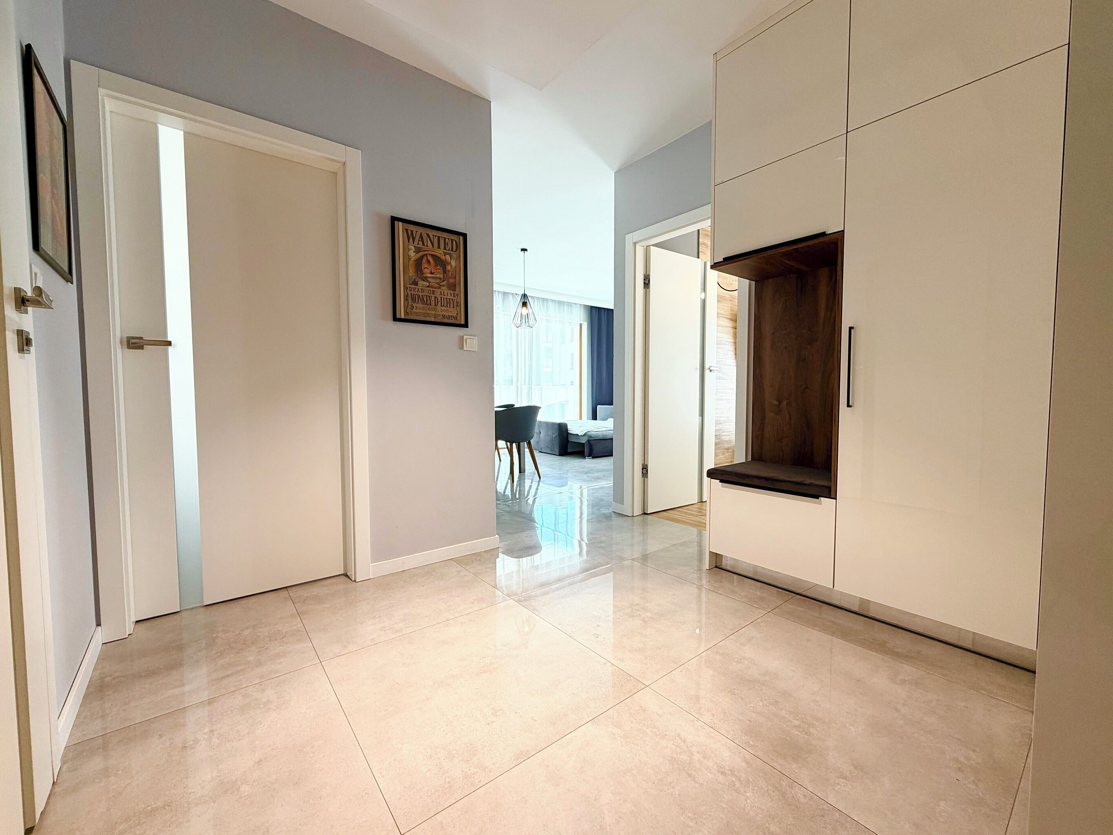 A hallway with a white door, a framed poster, and a wardrobe with a dark interior.