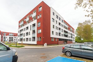 Ein mehrstöckiges Wohngebäude mit Balkonen, einem Parkplatz und einem Spielplatz.