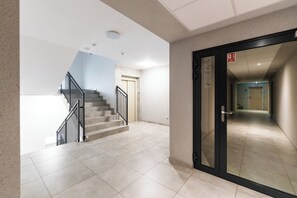A modern interior with a staircase, a door with emergency exit signage, and a hallway leading to another room. - Koszalińska Harmony Apartment (Kołobrzeg)