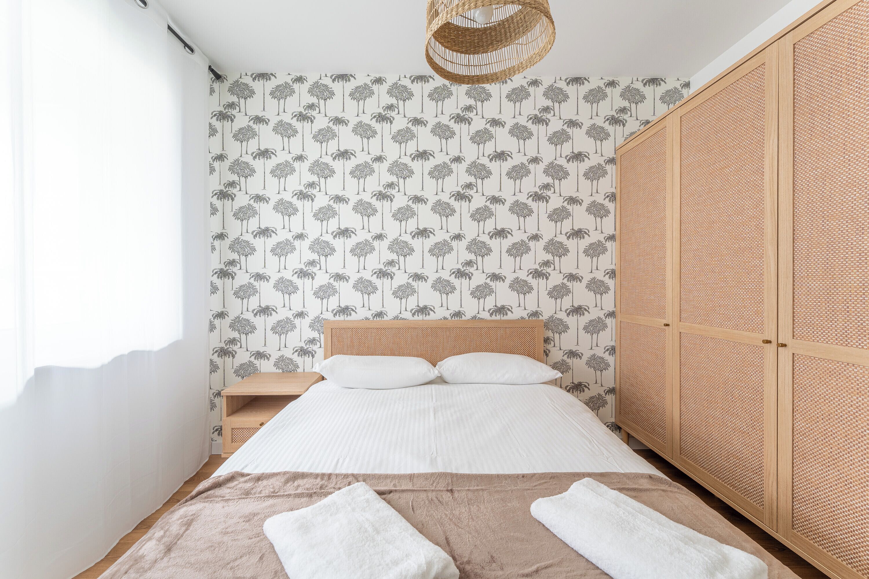 A bedroom with a bed, nightstand, wardrobe, and a hanging light fixture.