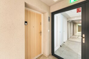 Ein Flur mit einer Holztür und einer Glastür, beide mit sichtbaren Griffen, und einem Schild über der Glastür.