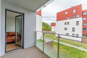 Ein Balkon mit Glastür, der zu einem Raum mit einem braunen Sofa führt.
