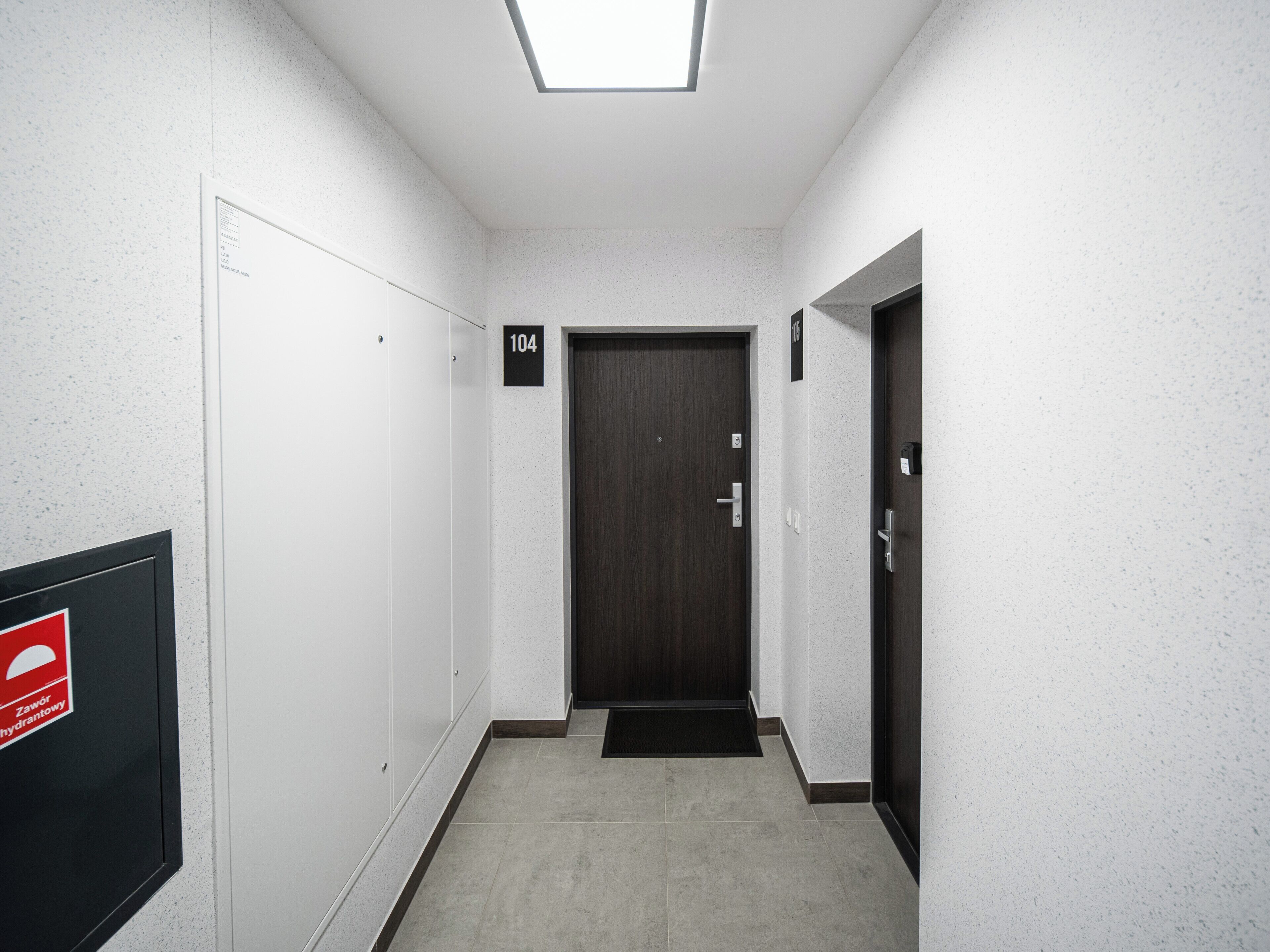 A hallway with a door marked '104' and a fire safety sign on the wall.