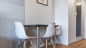 Un interior moderno con una mesa y dos sillas, un cuadro enmarcado en la pared y suelo de madera.